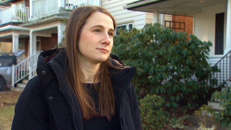 A woman with long brown hair looks at a reporter during an interview.