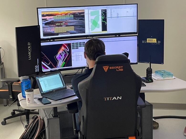 A man sitting at a desk with two large monitors.