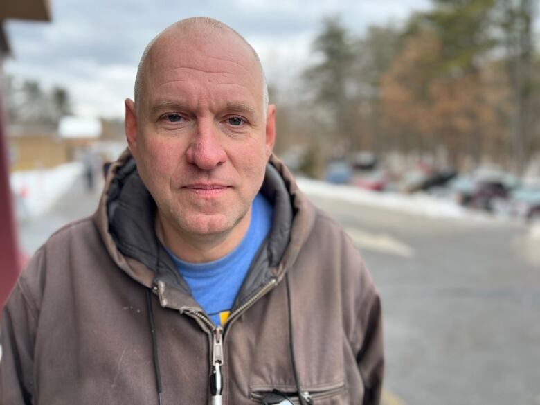 Man stares into camera with parking lot in background