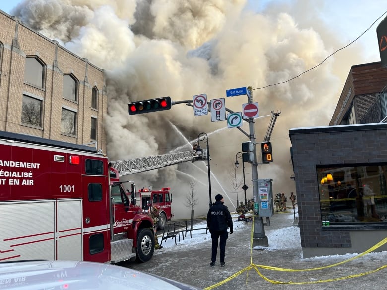 Smoke billows out of a building on a wintery street.