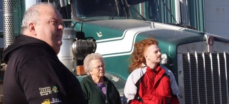 Levi Day and his dad Larry, and grandma Vi stand in front of a big rig at their family's business.