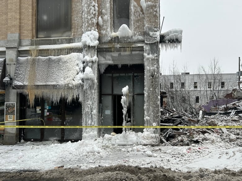 Frozen water and ice over a building. Next to the building is a pile of rubble. 