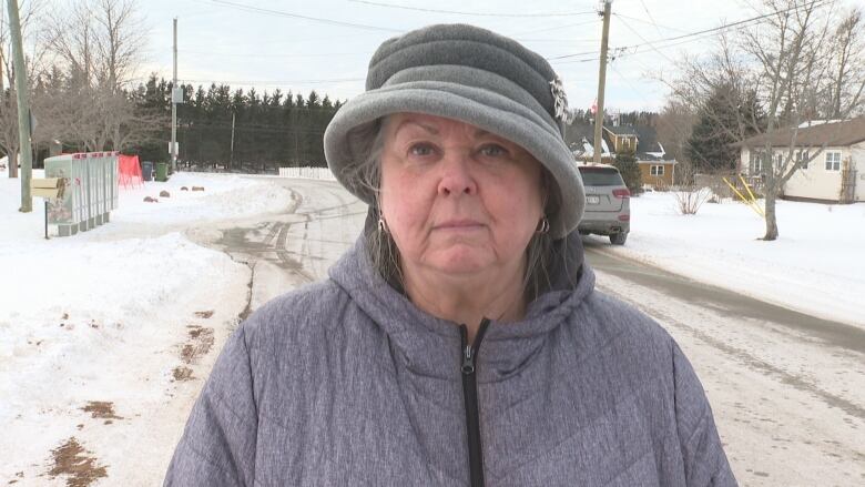 Woman standing in snow with grey hat.