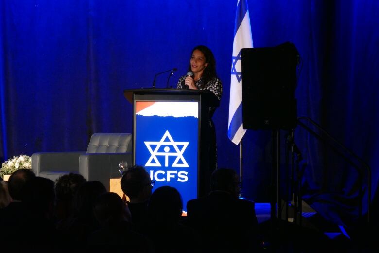 A woman speaking in front of a crowd.