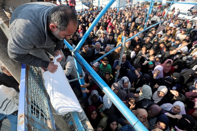 A Palestinian man holds a flour bag as others wait to receive theirs from the United Nations Relief and Works Agency.