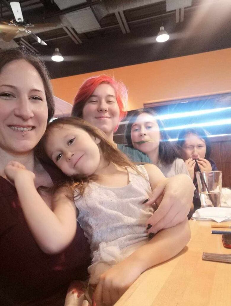 Raven Nichols sits at a table with her four children.    