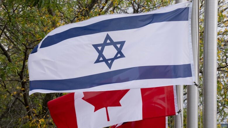 The Canadian flag and Israeli flag fly side by side. 