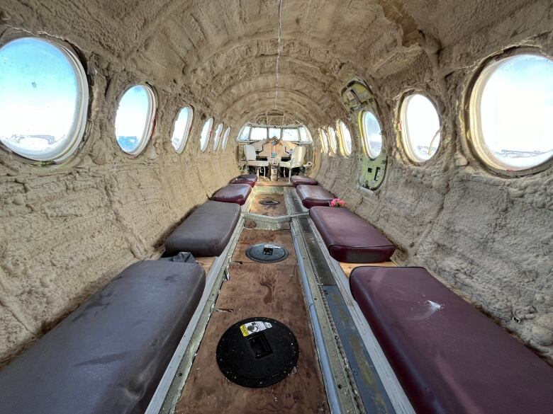 The inside of an old aircraft turned into an ice fishing shack, with bus benches installed along the walls.