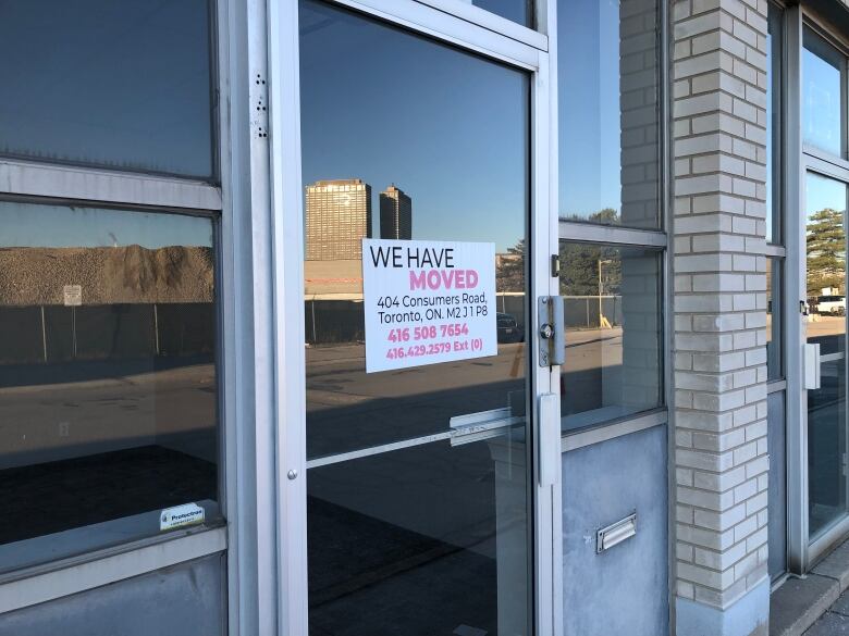 A Thorncliffe businesses with a sign saying we've moved Jan 2024, showing Metrolinx construction in the reflection.