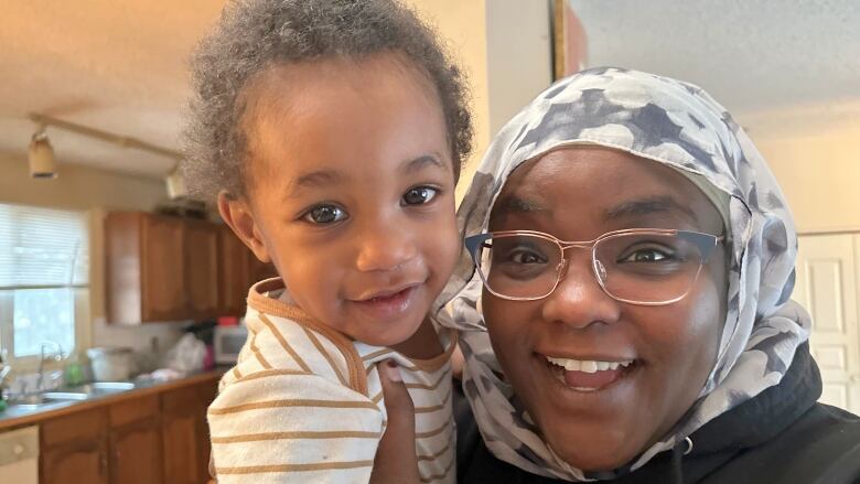 A woman holds a child and smiles for the camera