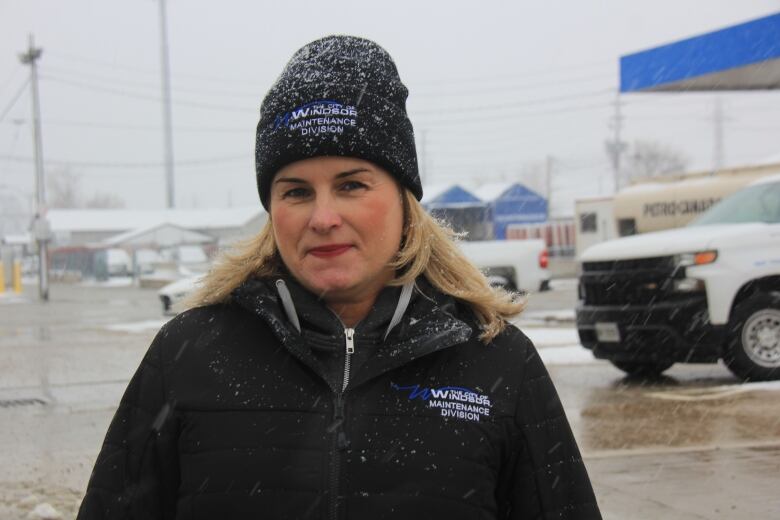 A woman wearing a black hat and a black jacket standing in the snow