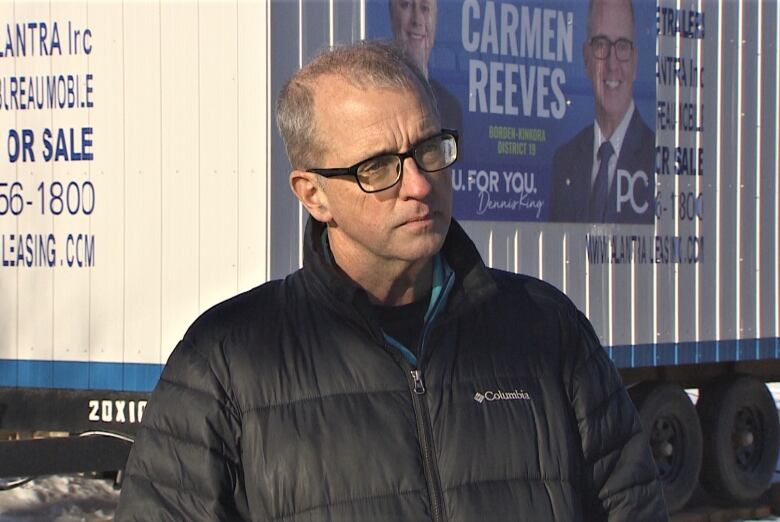 Carmen Reeves outside with campaign signs behind him.