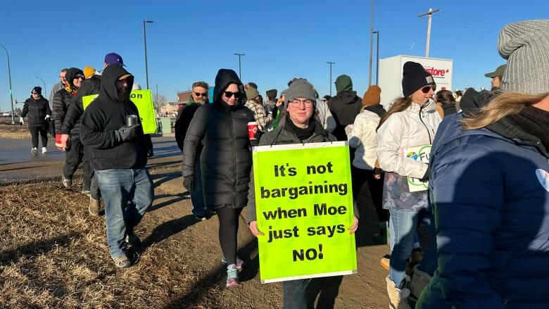 A group of picketers hold signs.