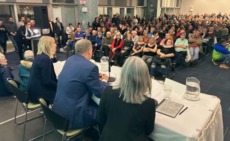 With Summerside Mayor Dan Kutcher looking on from the podium at the far left of the photo, the health minister, Health P.E.I. officials and members of the audience listen to a question being asked from the back of the room Thursday night. 