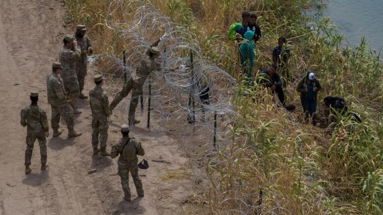 Members of the Texas National Guard, seen last September, fortifying razor wire along the bank of the Rio Grande river to deter migrants from entering into the U.S. in Eagle Pass, Tex.