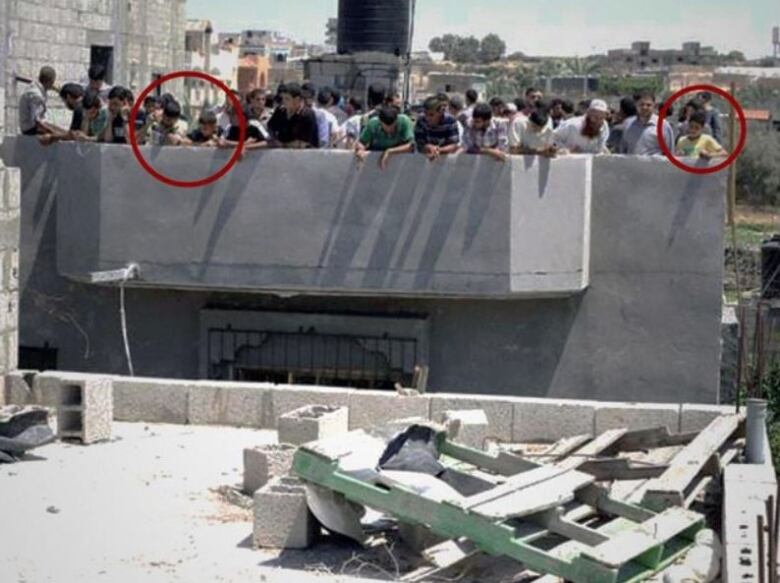 People gather on a rooftop surrounded by rubble.