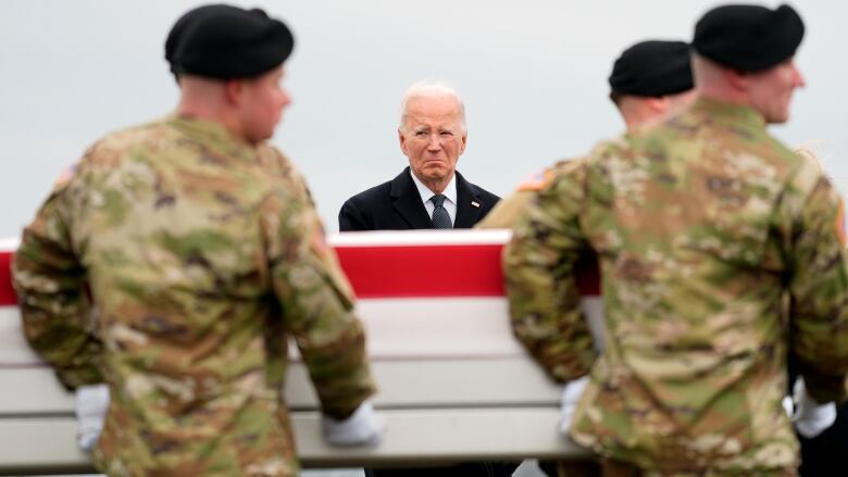 U.S. President Joe Biden watches four soldiers carry a casket.