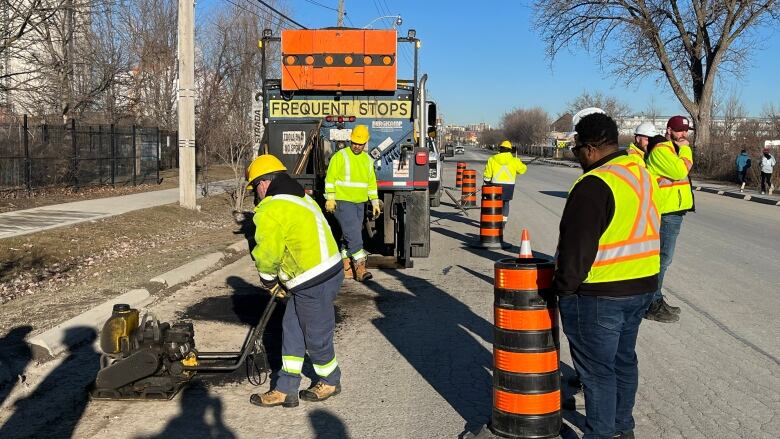 City crew workers repairing pot hole on the side of the road.