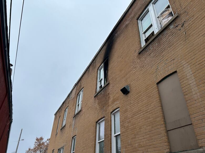 The side of a brick building. Bricks next to a window are charred.