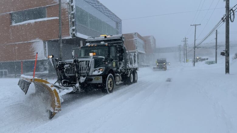 Two plows are shown clearing a snow-filled street in downtown Sydney, N.S.