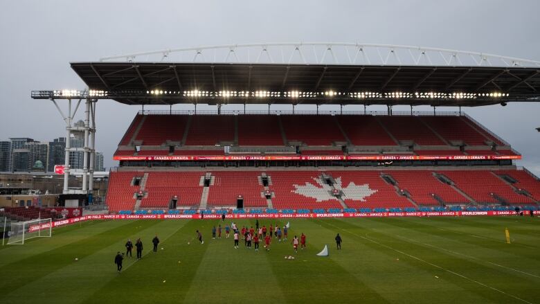 A wide shot of a soccer field with men's players practicing on it.