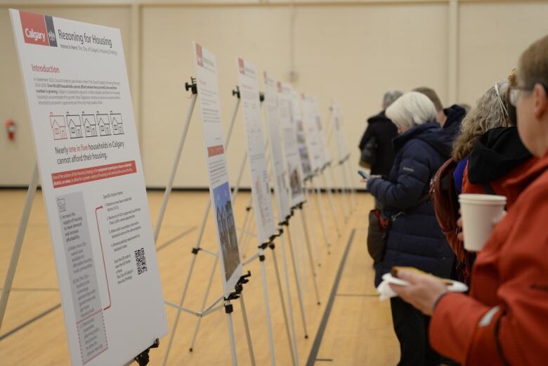 People stand in front of display boards at a city rezoning open house.