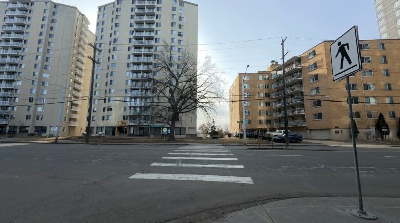 A pedestrian crosswalk on a street. A white pedestrian walking sign is shown on the right. 