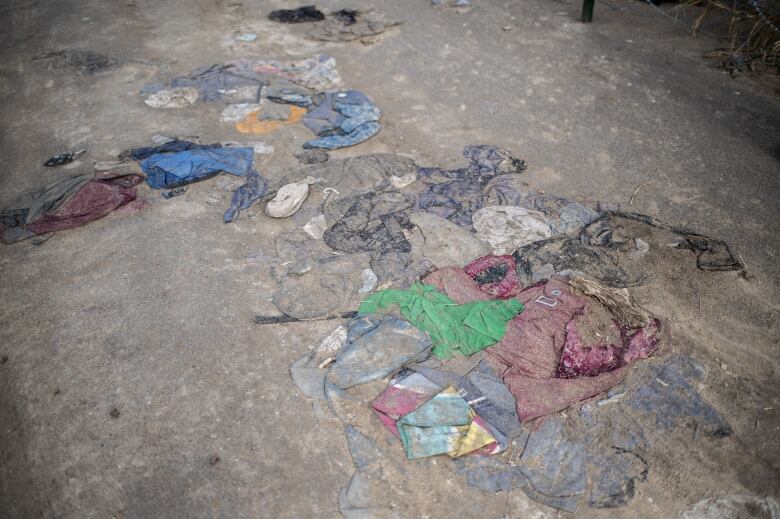 Several items of clothing of various colours are shown on a dirt path.