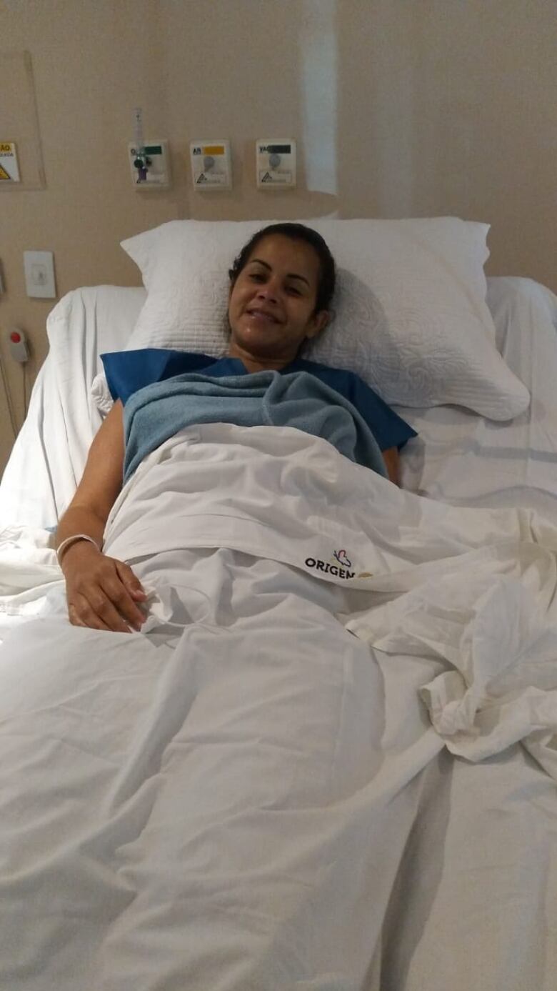 A young woman smiles from a hospital bed.