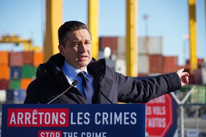 A man standing in front of a podium with a sign that reads: Arretons les Crimes/Stop the Crime