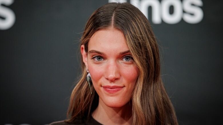 A woman gives a slight smirk in a close up portrait photo. 