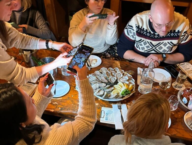 A group tasting and taking photos of oysters at a restaurant