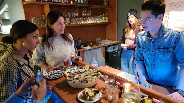 People gathered around a counter full of shucked oysters 