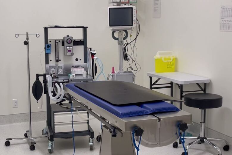 White room with an operating table with a blue mat and a black cover