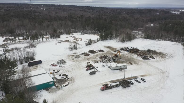 Heavy equipment near piles of snow covered scrap material.