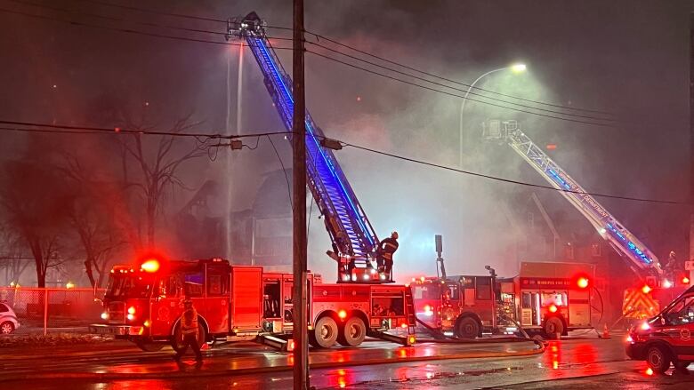 Fire trucks around a building covered in smoke