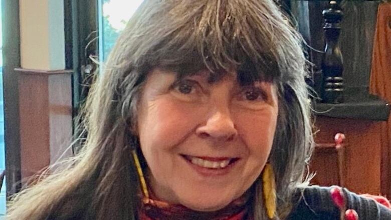 A woman with long grey hair smiling at the camera.