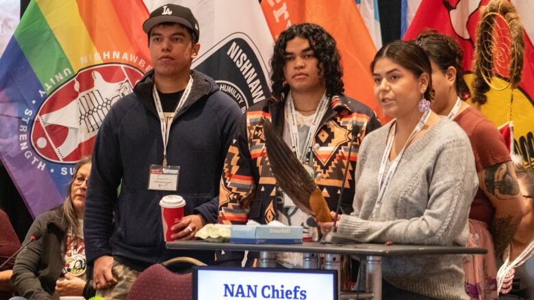 A group of young people gather around a podium. 