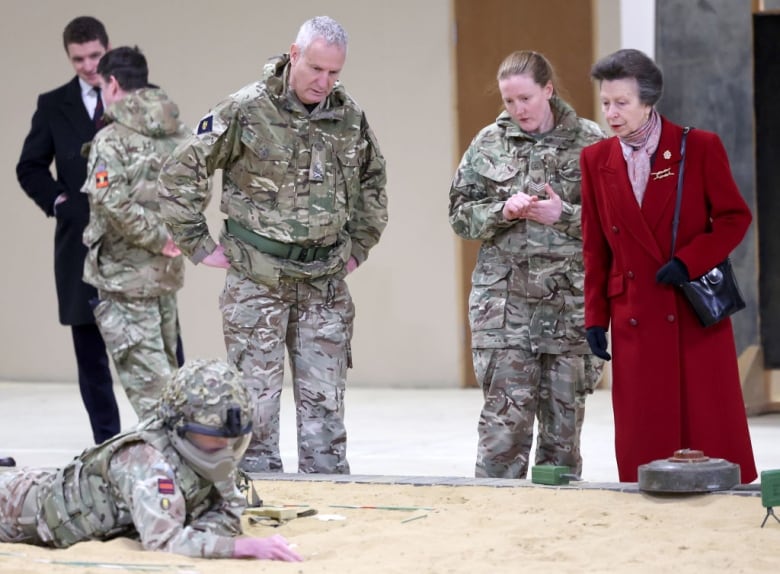 A person looks at soldiers demonstrating a training exercise.