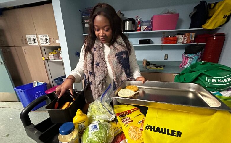 A woman putting food in a metal tray.