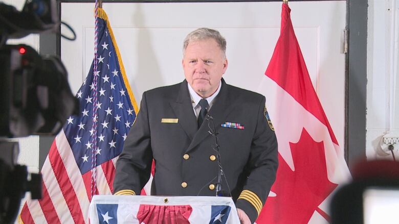 A man stands at a podium wearing a uniform