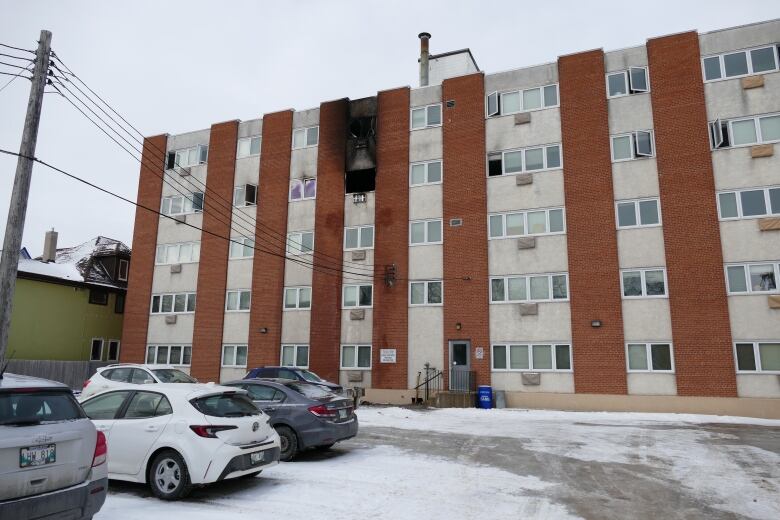 The outside of an apartment building shows fire damage.