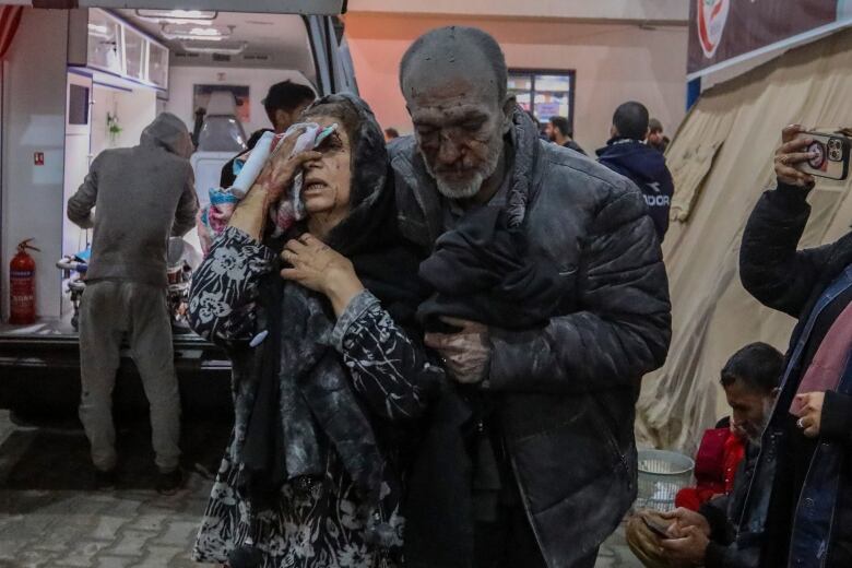 People covered in dust and blood enter a hospital.