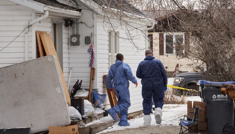 Police walk around the outside of a house.