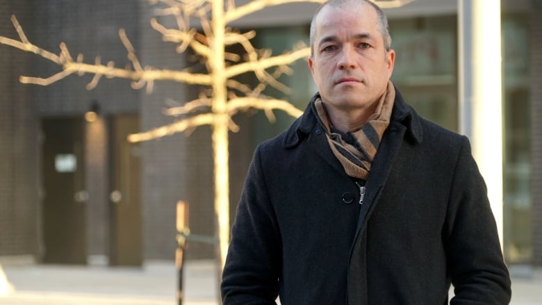 A man wearing a black winter coat and a brown scarf.