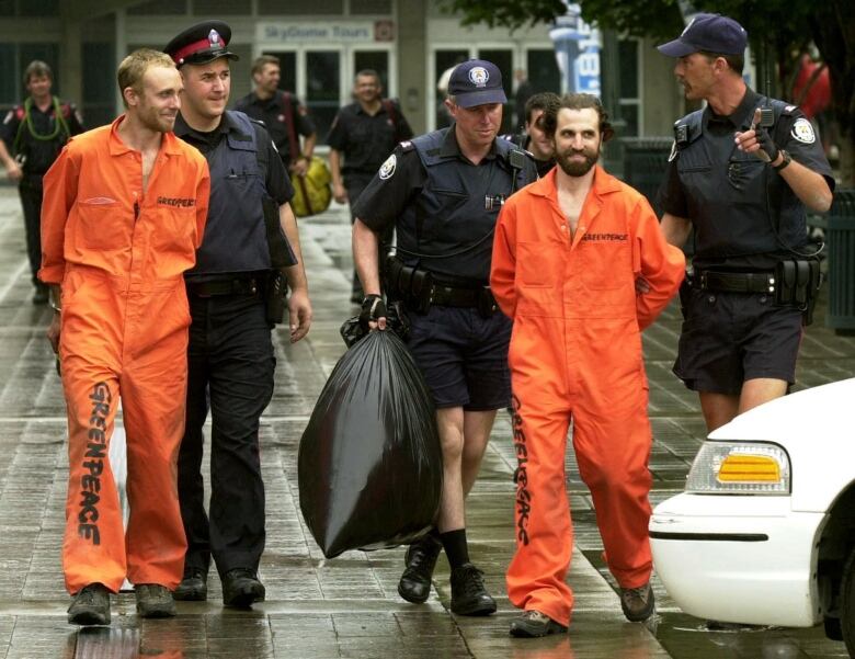 Greenpeace activists Steven Guilbeault, right, 31, and Chris Holden, 23, are led by officials from the CN Tower in Toronto Monday July 16, 2001. Guilbeault and Holden scaled 346 metres (1,136 ft.) on the world's tallest free-standing structure to protest Canada's role in changing the world's climate.