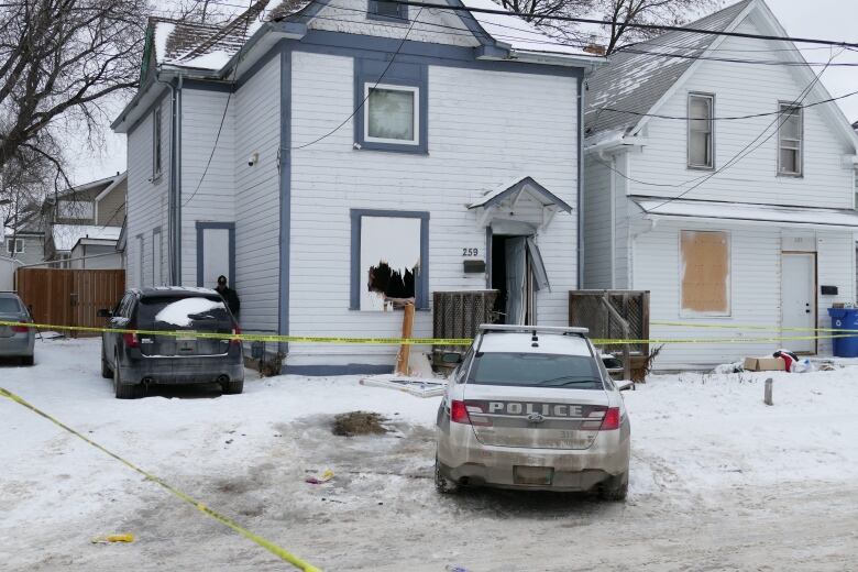 A police car is parked outside a home taped off with yellow police tape.