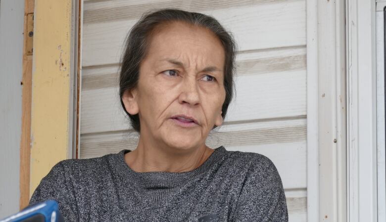 A woman stands outside a house.