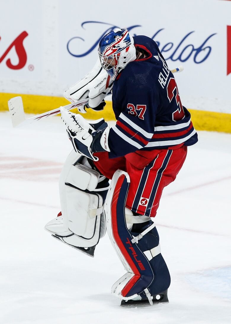 A hockey goalie in blue and red celebrates a win.