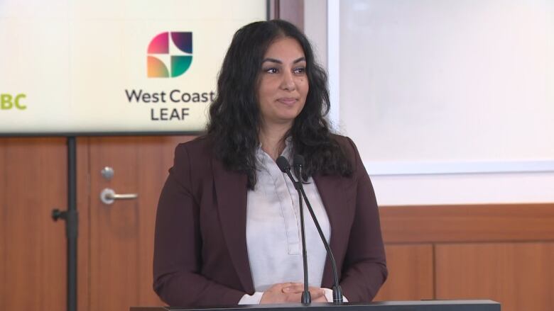 A woman stands at a microphone.